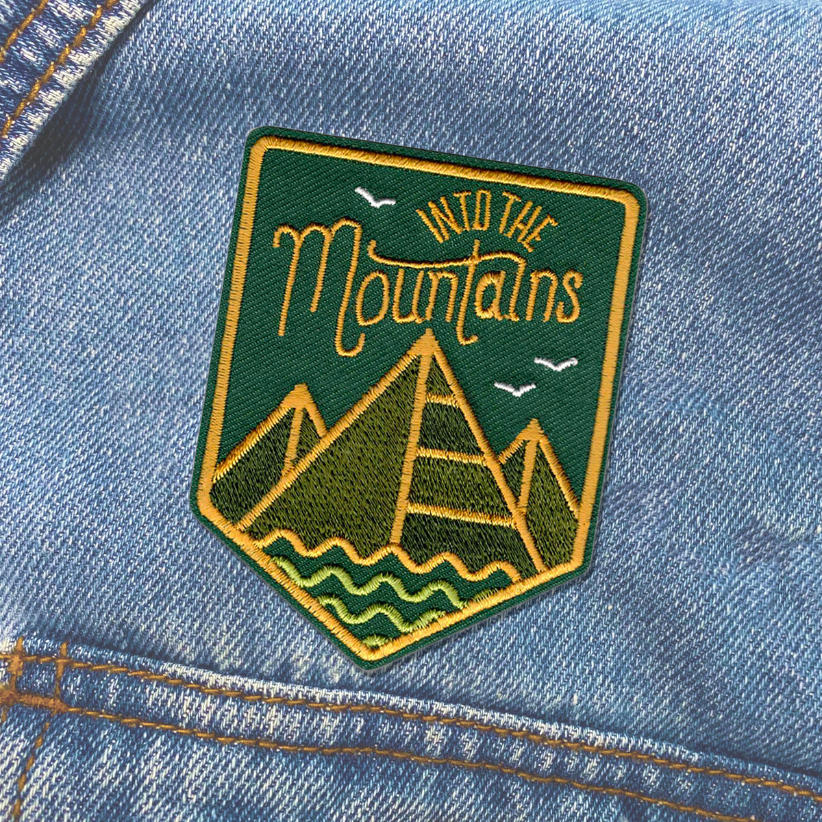 A denim jacket with an Into The Mountains Patch from KosmicSoul sewn on.