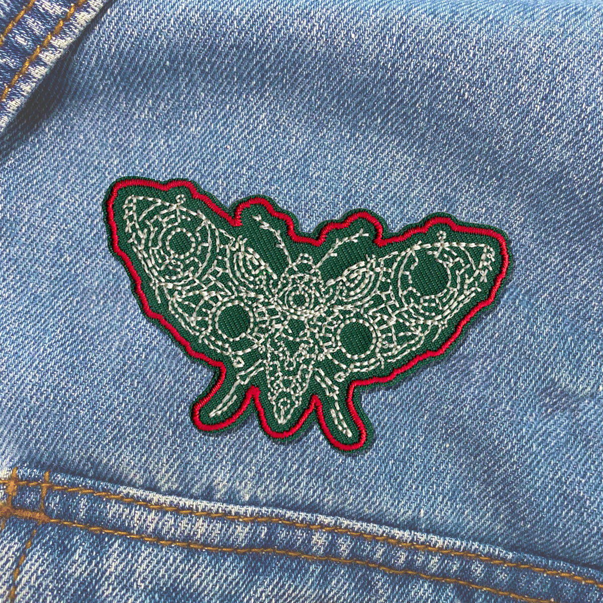 A green and red Butterfly Moth Patch sewn on a denim jacket by KosmicSoul.