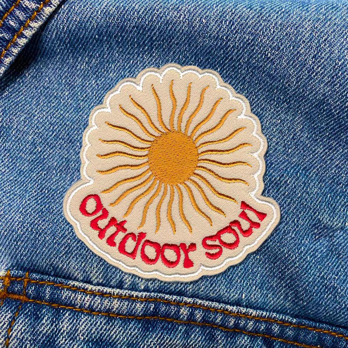 A KosmicSoul Outdoor Soul Patch with a sun on it ironed on in a jeans pocket.