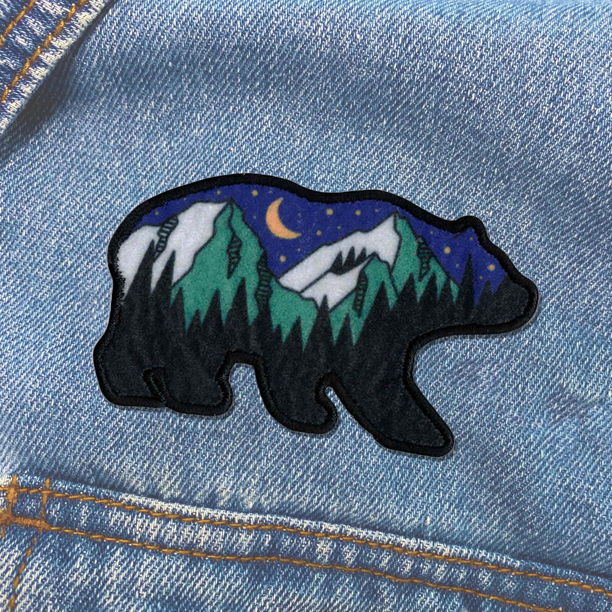 A denim jacket with the KosmicSoul Outdoor Bear Patch sewn on it.