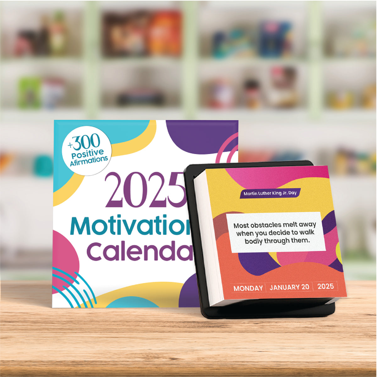 The 2025 Motivational Calendar by Kosmic Soul is displayed on a countertop, featuring 300 positive affirmations. This day-to-day calendar includes quotes like one for Martin Luther King Jr. Day, which reads, &quot;Most obstacles melt away when you decide to walk boldly through them.&quot; It’s perfect for a desk or tabletop display.